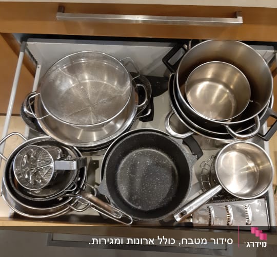 סירים ומחבתות מסודרים במגירת מטבח